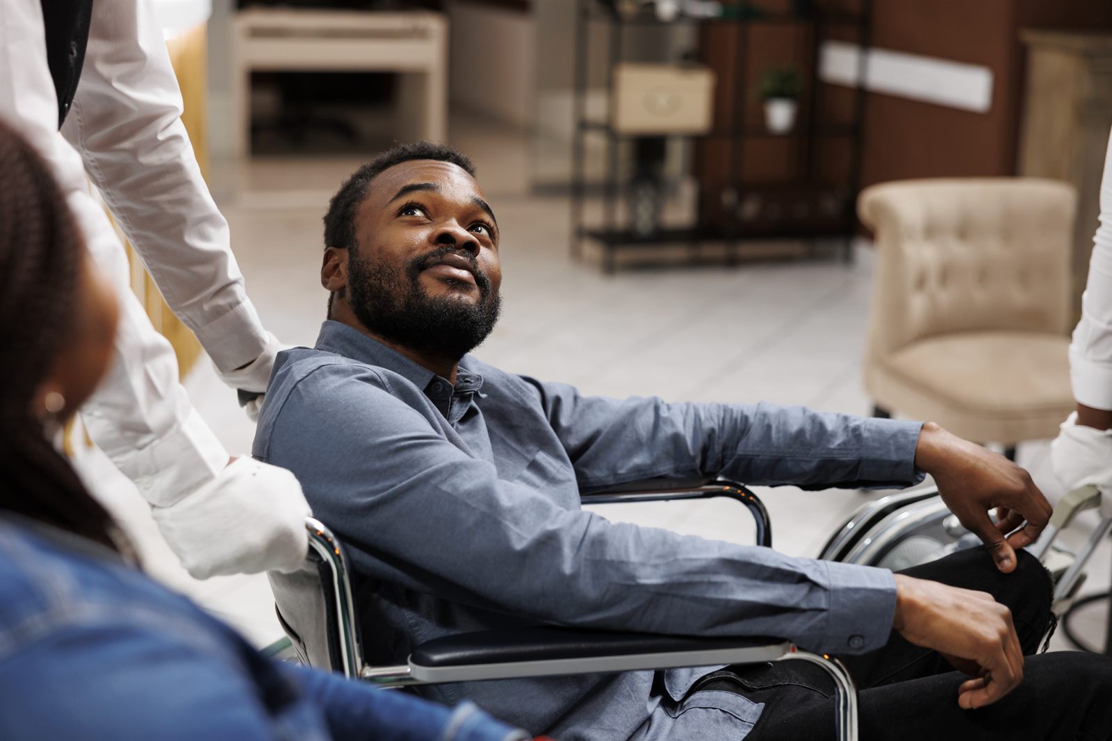 Smiling man in a wheelchair chatting with companions in a hotel lounge
